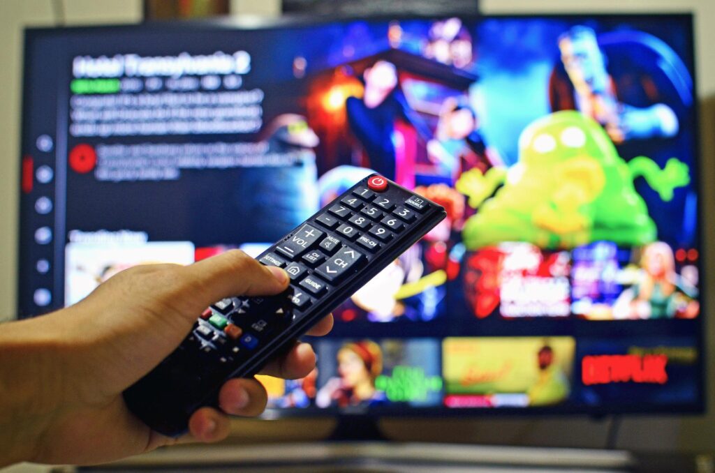 ストリーミング配信を表示するテレビとリモコンを持つ手