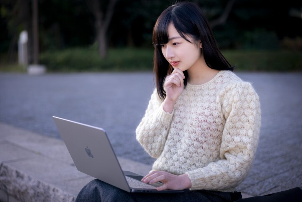 屋外でノートPCを見る女性